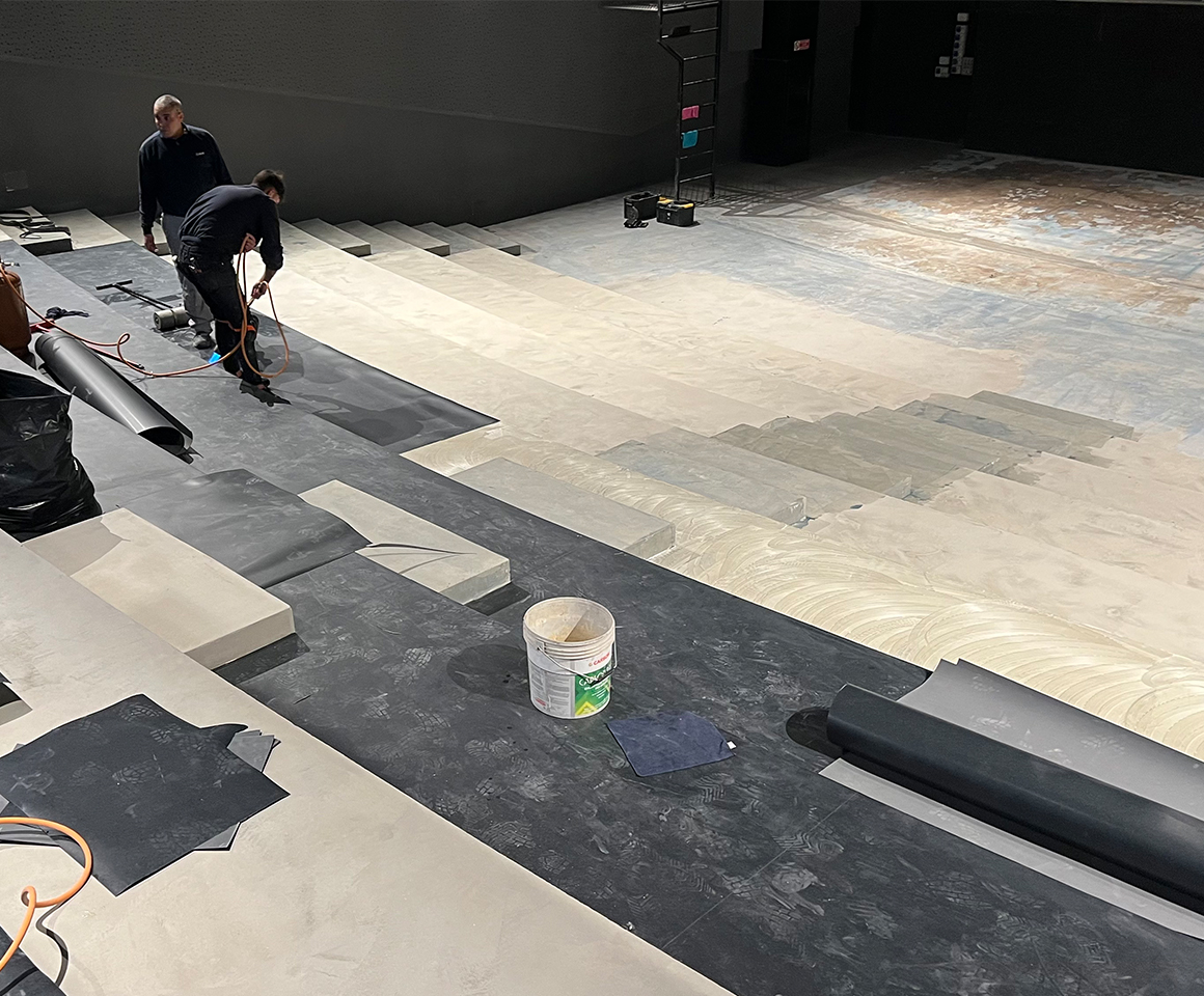 Cantiere con fasi di incollaggio rotoli di pavimento in gomma per sala cinematografica.