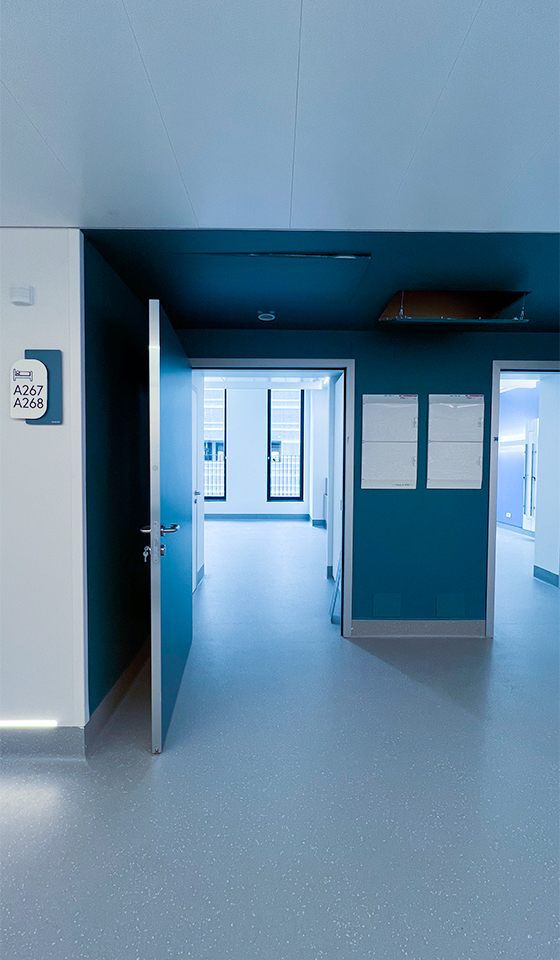 Pavimento tecnico in PVC per reparto corridoio ospedale con rivestimenti murali e illuminazione zoccolino profili.