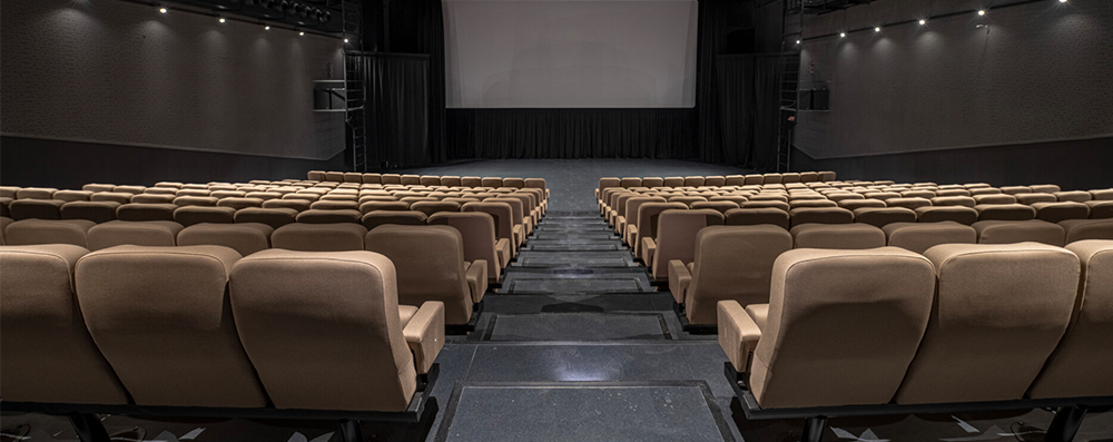Sala cinematografica con pavimento in gomma, gradini e poltroncine per il pubblico